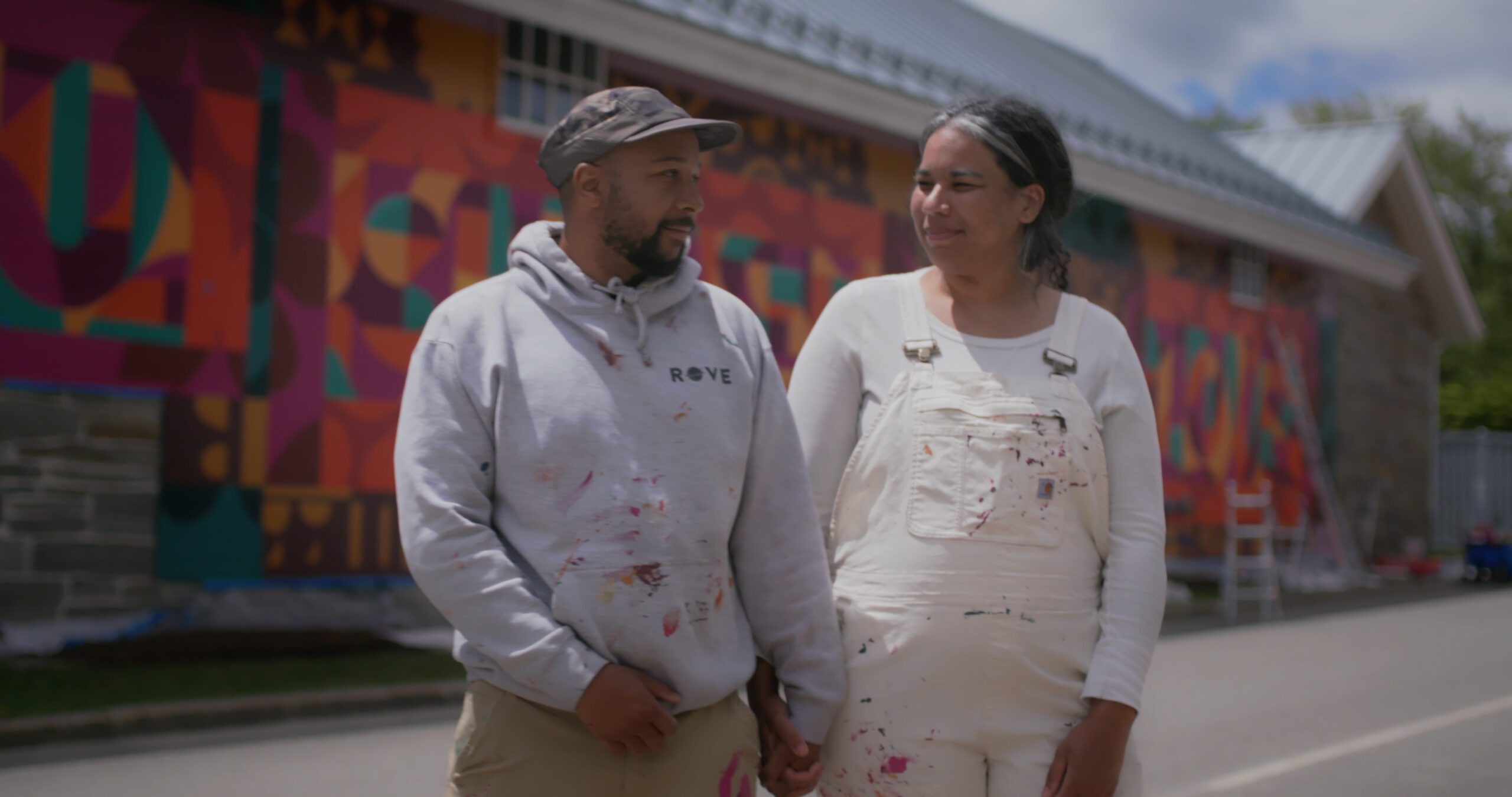 couple standing in front of a mural on the side of a building